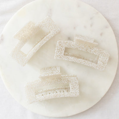 Three decorative hair clips on a white marble surface