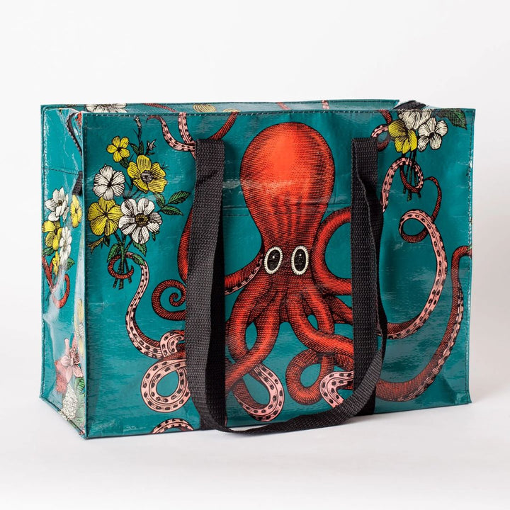 A rectangular shoulder tote bag with black handles, featuring a large red octopus with swirling tentacles against a teal background, surrounded by yellow and white flowers.