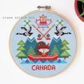 Cross stitch kit with a design of a person in a canoe, trees, and the word 'Canada' on a blue background.