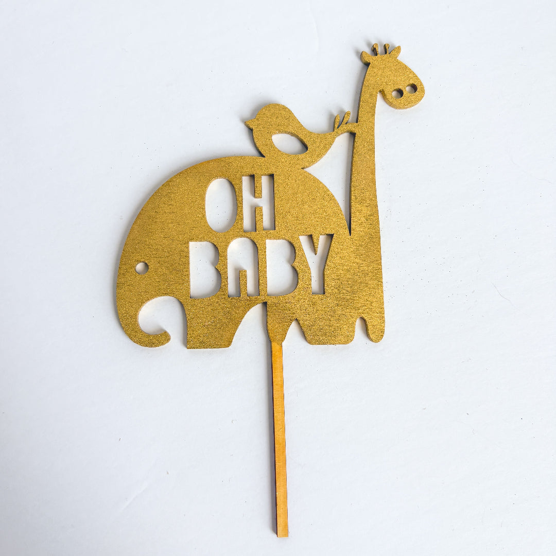 Gold cake topper shaped like a giraffe with 'OH BABY' text on a white background