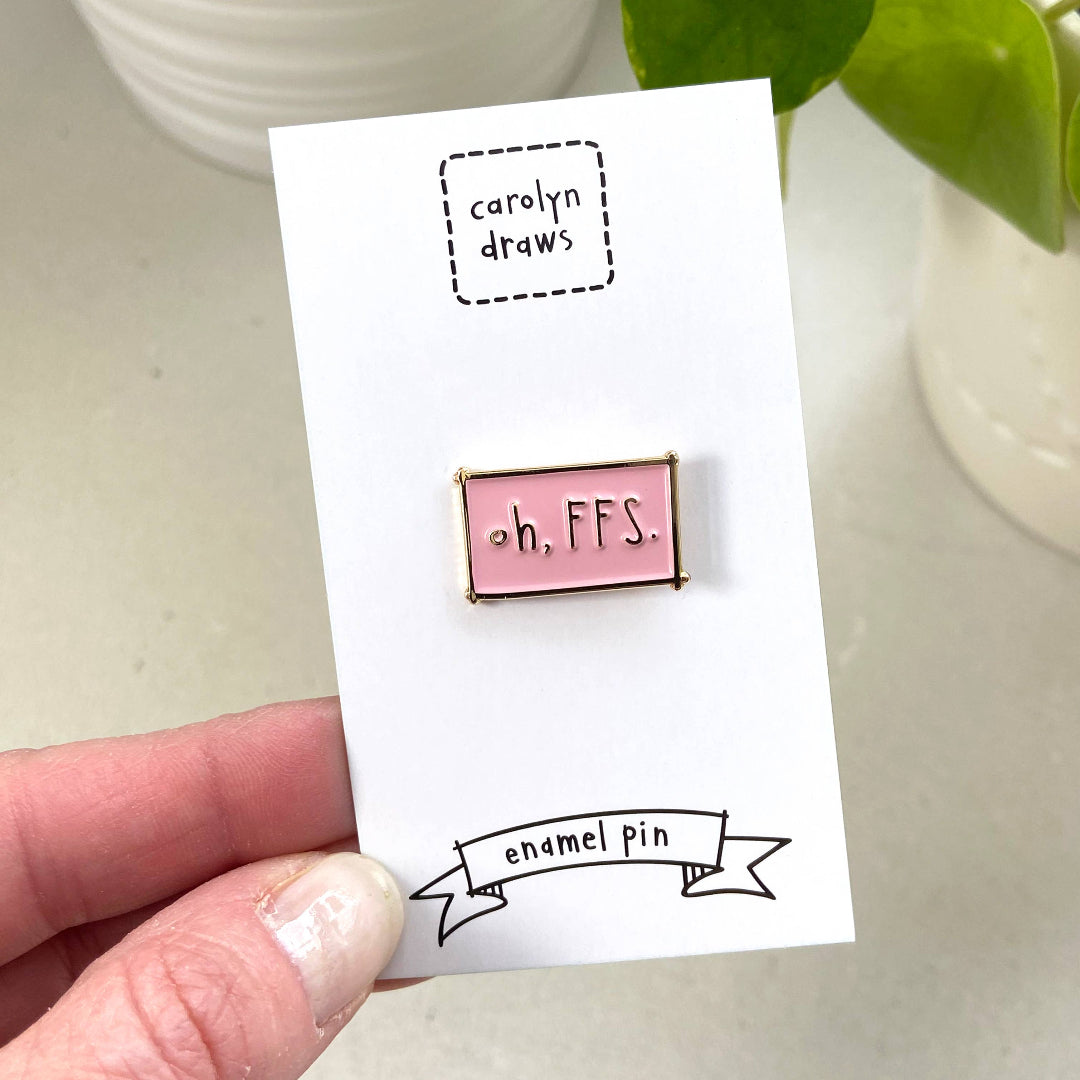 Pink enamel pin on a card with 'carolyn draws' branding