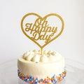 White cake with colorful sprinkles and a gold 'Oh Happy Day' heart-shaped topper on a white background