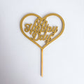 Gold heart-shaped cake topper with 'Oh Happy Days' text on a white background