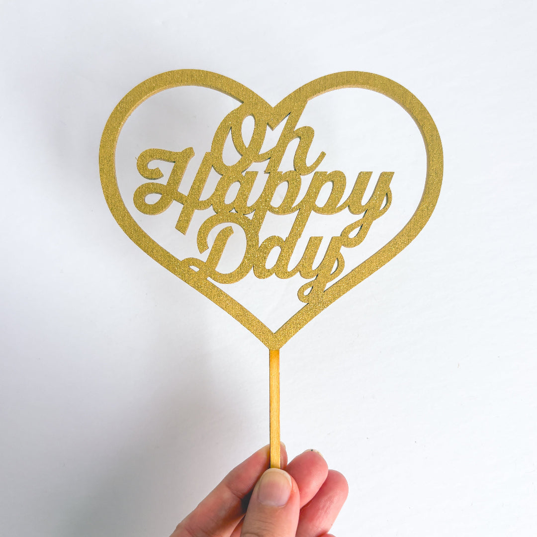 Gold heart-shaped 'Oh Happy Day' decoration on a white background