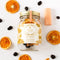 A glass jar filled with dried orange slices, dried cherries, and other ingredients. The jar has a white label with the Maiden Voyage logo and the product name 