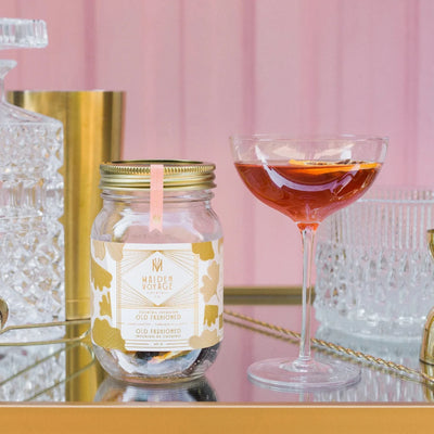 A glass jar filled with dried orange slices, dried cherries, and other ingredients. The jar has a white label with the Maiden Voyage logo and the product name 