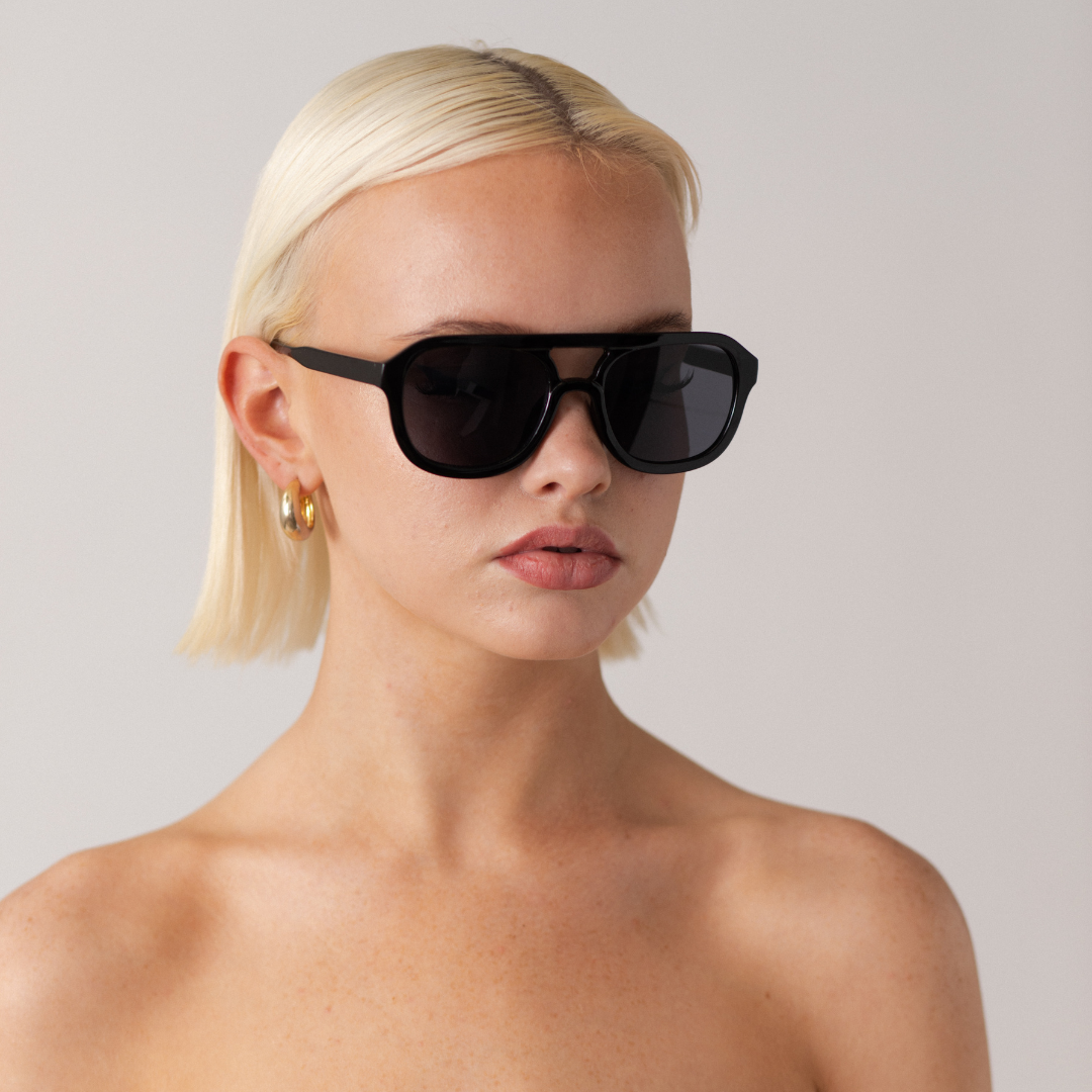 Woman wearing black sunglasses against a plain background