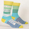  pair of men's crew socks with a vibrant stripe pattern. One sock features wide horizontal green and blue stripes, while the other has blue and white stripes on the foot and green and white stripes on the calf. Text on the socks reads 