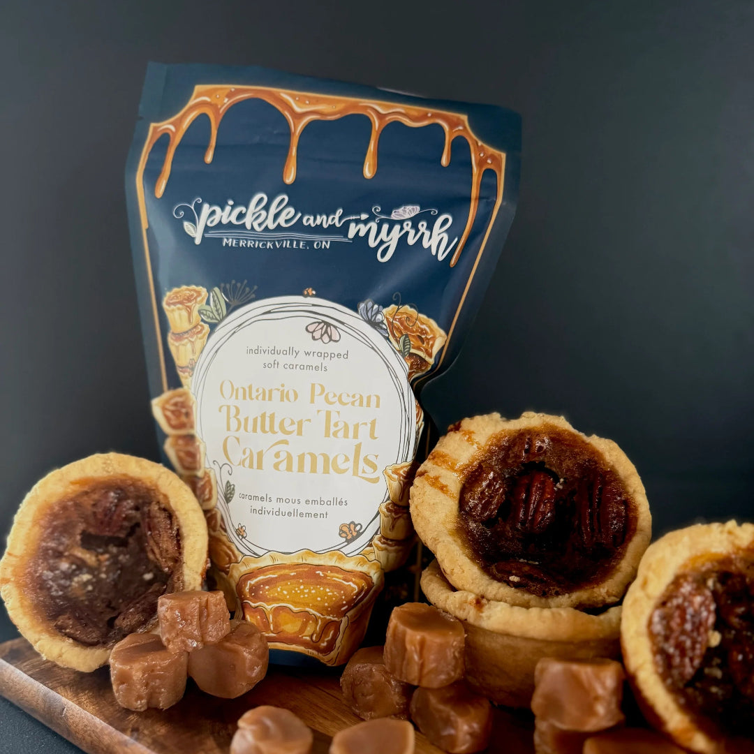 Pecan pie butter tart caramels with a package labeled 'Jickle and Jiggle' on a wooden board.