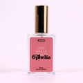 A bottle of Charleston & Harlow perfume named "Ophelia." The bottle is clear glass with a gold spray cap. The label is pink with the brand name and perfume name in a bold, playful font. The fragrance notes are listed as "Spice, Vanilla, Tobacco."