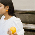 Woman holding an orange against a neutral background
