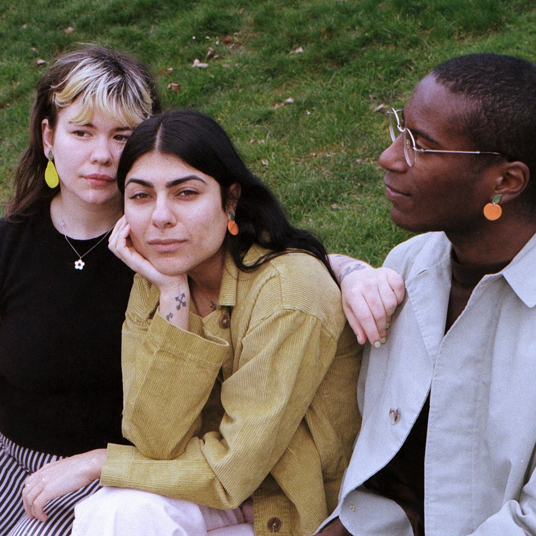 Three people sitting together on a grassy field