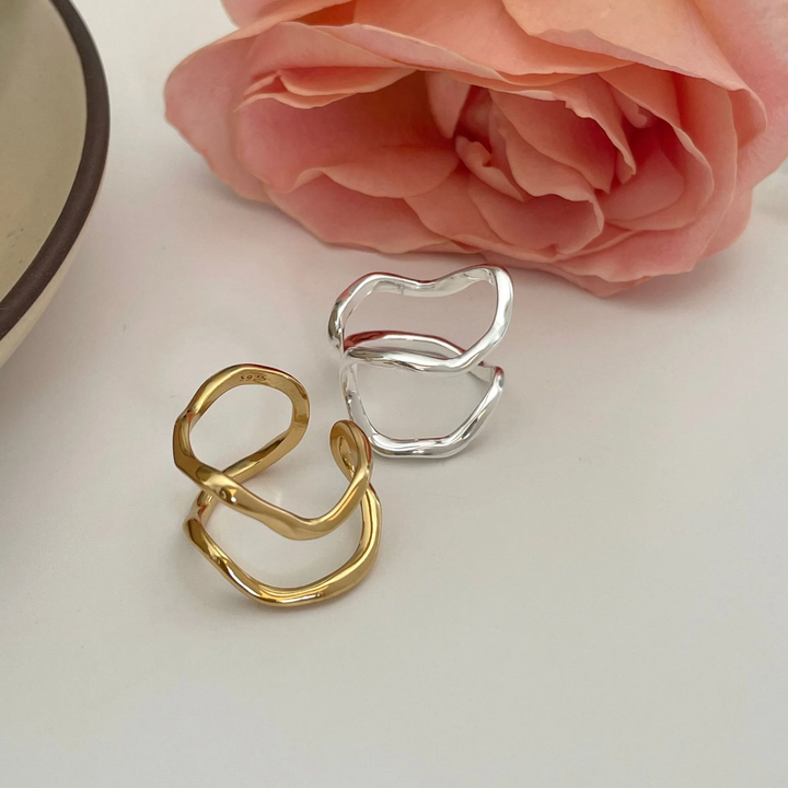 Two organic shaped adjustable rings, one in sterling silver and one in gold plating, featuring a fluid, abstract, double wave design, displayed on a white background. These modern rings are available in Ottawa, Ontario, Canada.