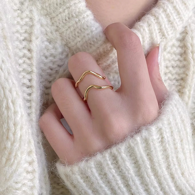 organic shaped adjustable rings, in gold plating, featuring a fluid, abstract, double wave design, displayed on a white background. These modern rings are available in Ottawa, Ontario, Canada.