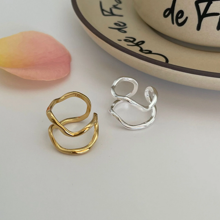 Two organic shaped adjustable rings, one in sterling silver and one in gold plating, featuring a fluid, abstract, double wave design, displayed on a white background. These modern rings are available in Ottawa, Ontario, Canada.