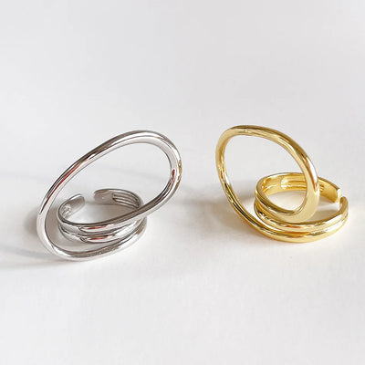 A set of silver and gold-plated geometric open statement twist rings, featuring unique, flowing designs, displayed side-by-side on a light-colored surface. These are modern and bold rings, available in Ottawa, Ontario, Canada.