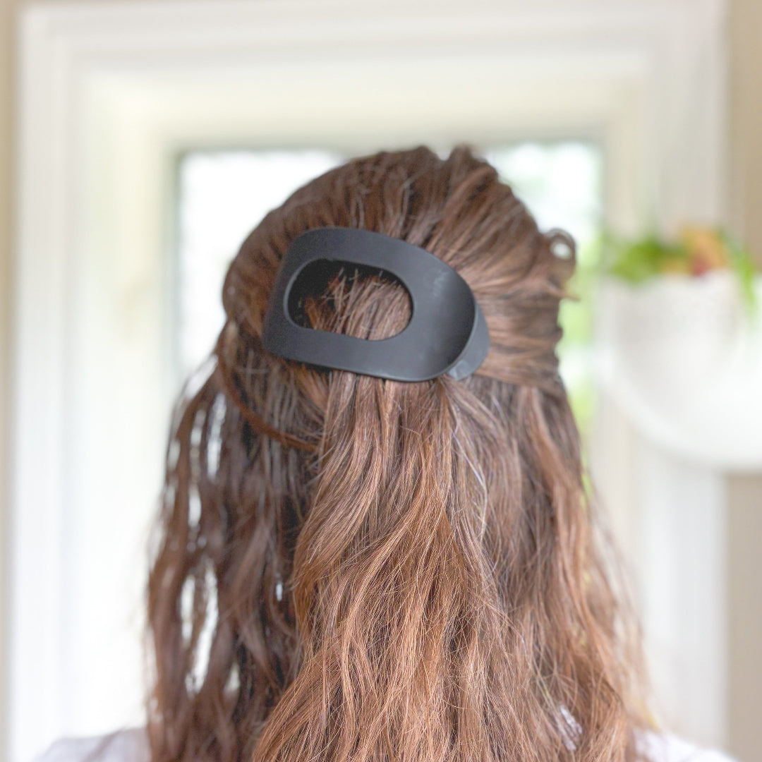Person with a black hair tie in their hair, blurred indoor background