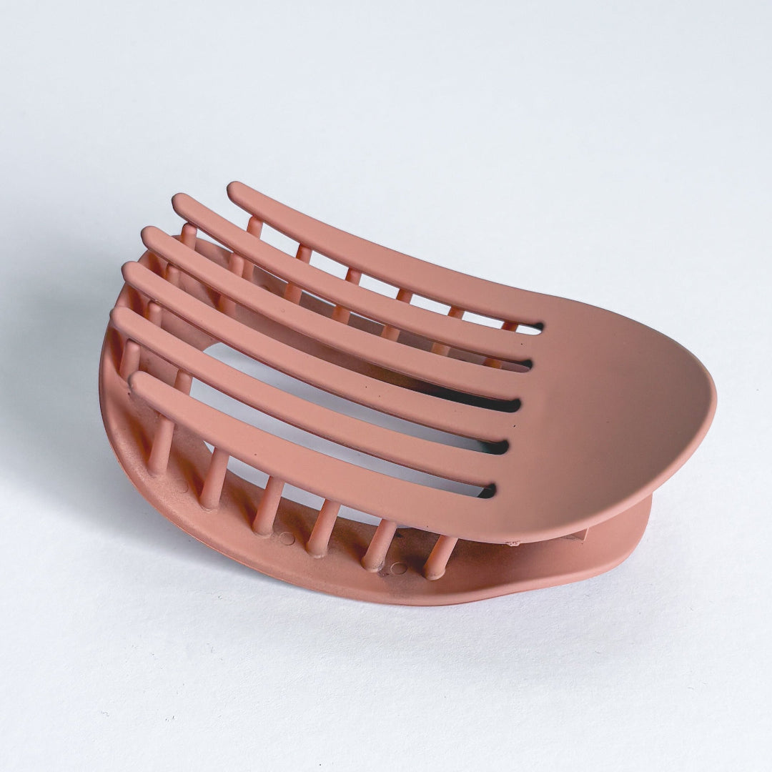 Pink soap dish with slotted design on a light gray background