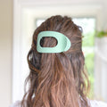 Green hair clip in a person's hair with a blurred background
