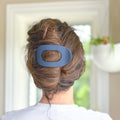 Person with a blue hair clip in their bun, blurred indoor background
