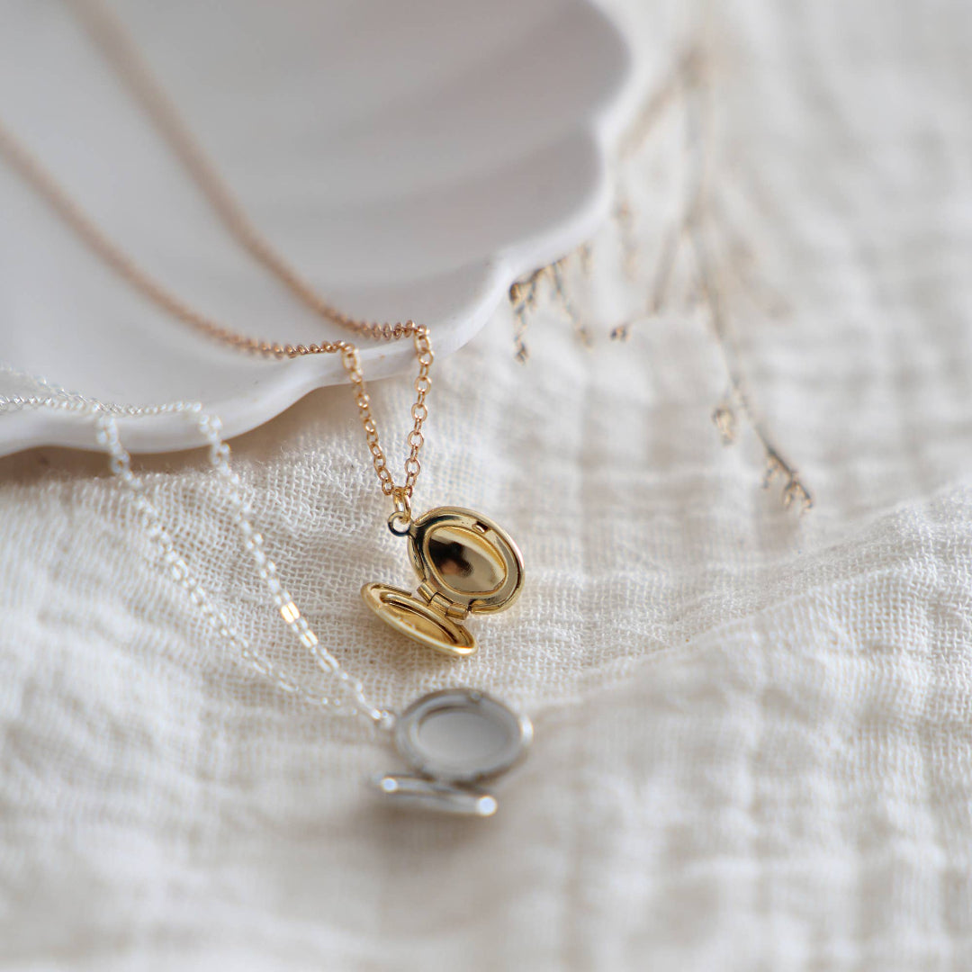 Gold necklace with a lock-shaped pendant on a soft fabric background