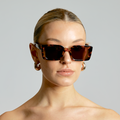 Woman wearing a pair of sunglasses with a plain background