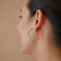 A pair of delicate 14 KT gold hoop earrings, each partially threaded with small Japanese glass seed beads in a pattern of light blue, white, black, and coral. The beads cover approximately half of each hoop, leaving the remaining gold wire visible.