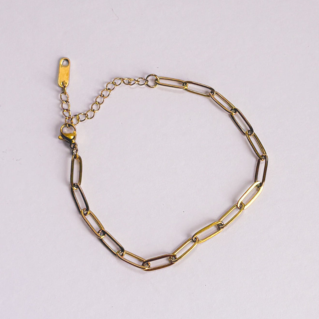 Gold chain bracelet on a light gray background