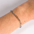 Silver chain bracelet on a wrist with a neutral background