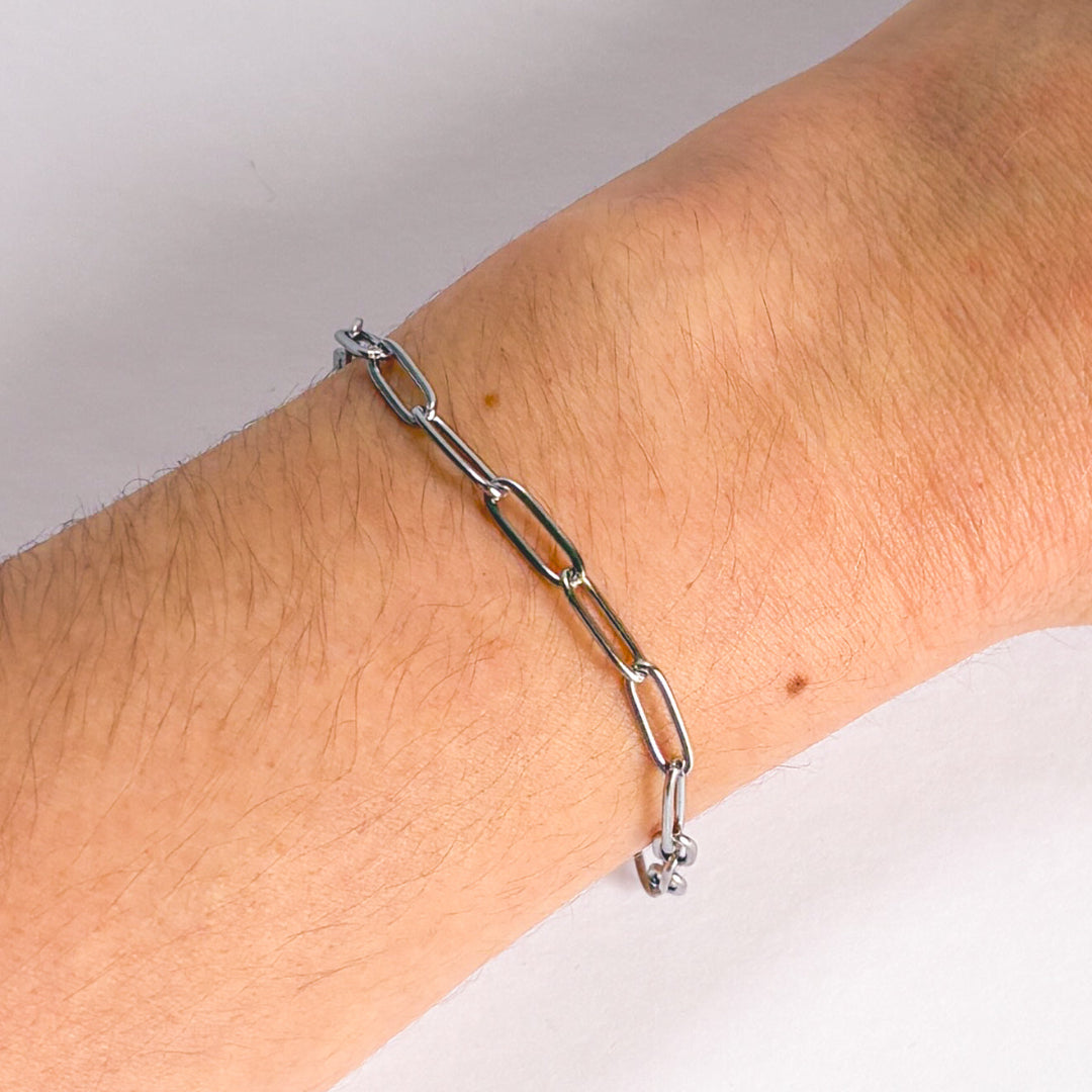 Silver chain bracelet on a wrist with a neutral background