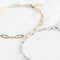 Two bracelets on a white surface. One bracelet is gold-colored, and the other is silver-colored. Both bracelets have a chain link design made of small, rectangular links.