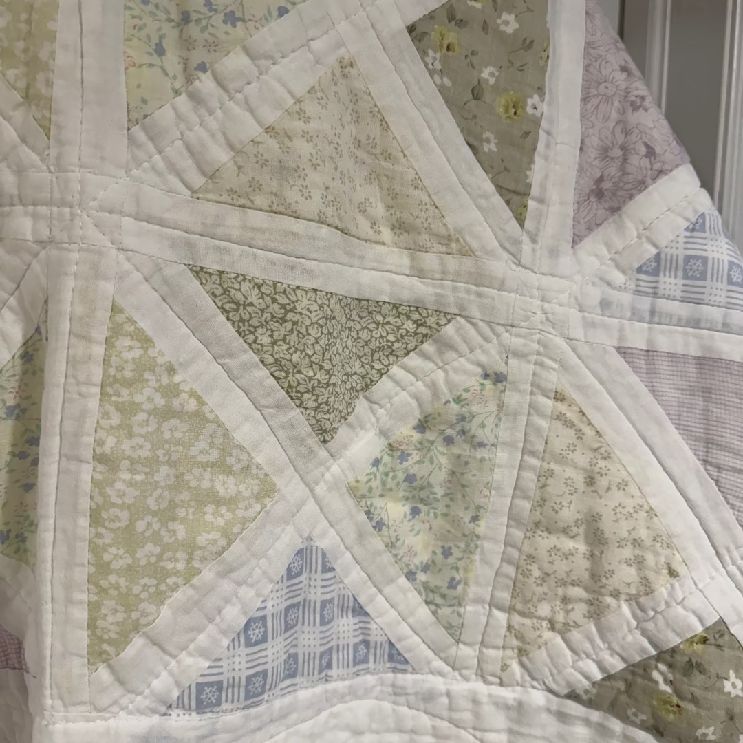 Quilt with geometric pattern featuring triangles and floral patterns.