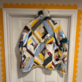 Colorful quilt draped over a white door with decorative yellow trim.