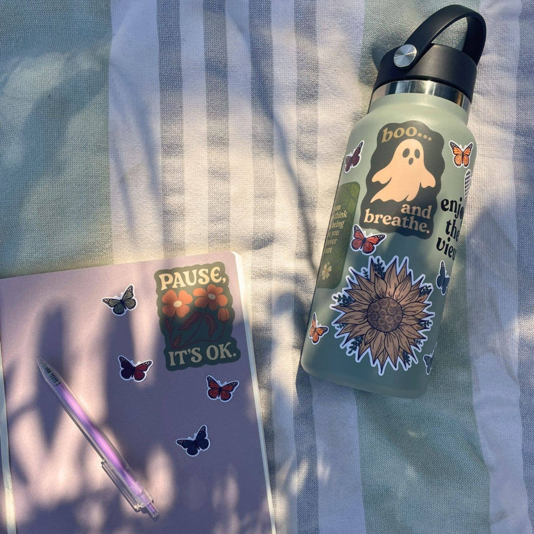 Water bottle with stickers and a notebook on a striped fabric background