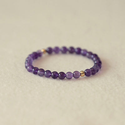 Purple beaded bracelet on a beige background