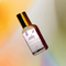 A clear spray bottle with a gold cap and a label that reads 