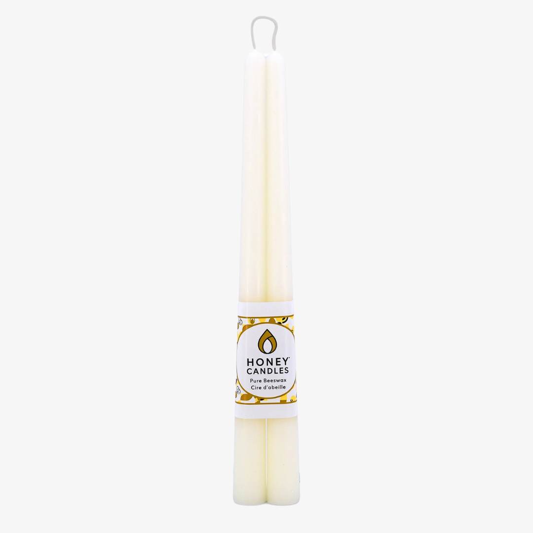 Two cream-colored beeswax candles are standing upright, tied together with a string. The candles have a label that says "HONEY CANDLES Pure Beeswax."