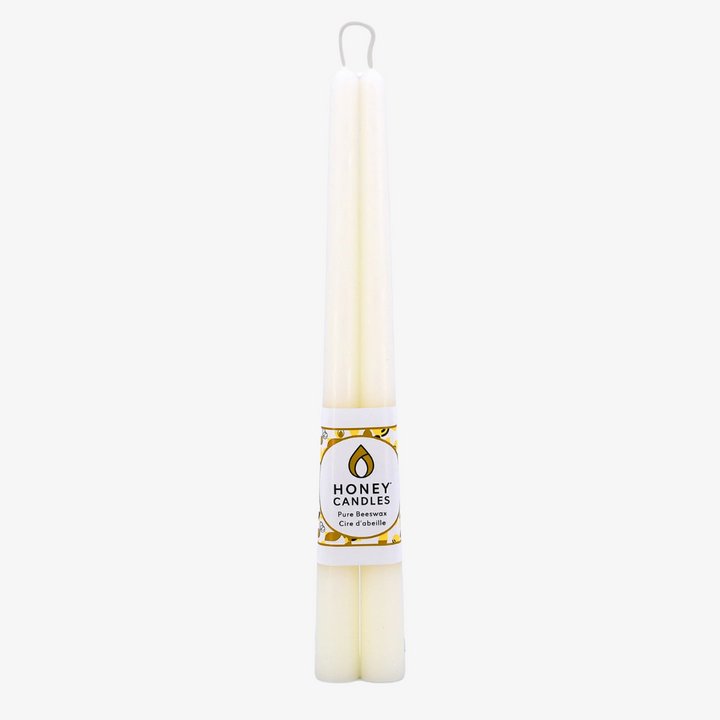 Two cream-colored beeswax candles are standing upright, tied together with a string. The candles have a label that says 