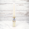 Two cream-colored beeswax candles are standing upright, tied together with a string. The candles have a label that says 