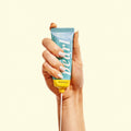 Hand holding a tube of 'Pearl' product against a white background