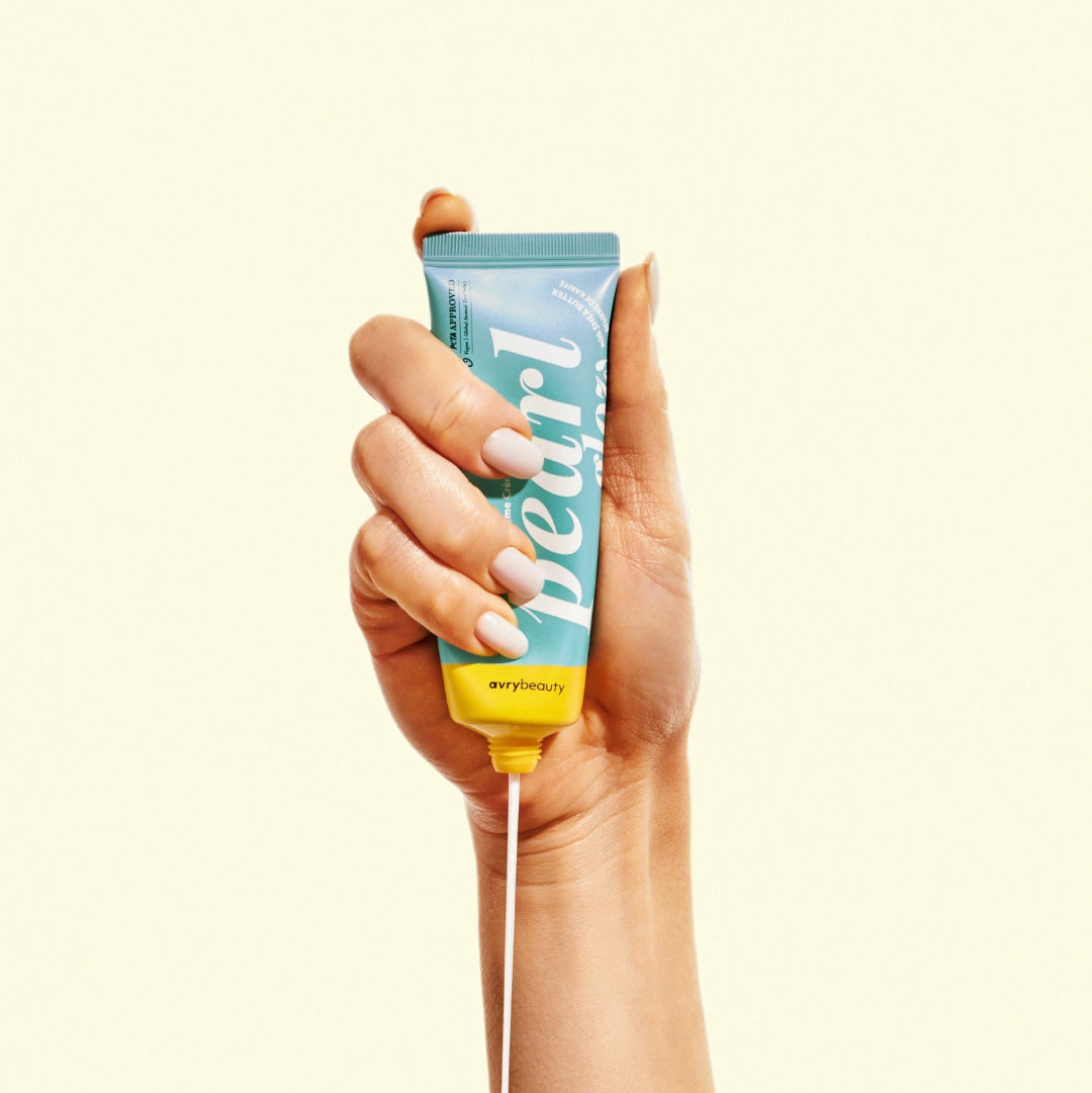 Hand holding a tube of 'Pearl' product against a white background