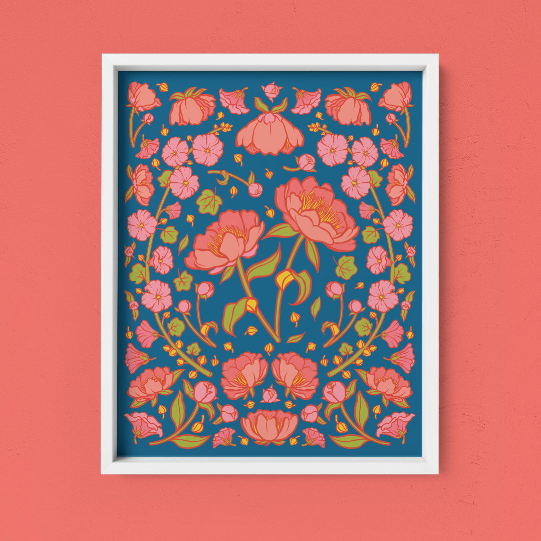 Framed floral artwork with pink flowers on a blue background against a coral wall.