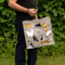 A reusable tote bag with a cat-themed design. The bag is a light grey color with black handles. It features a variety of cats in different poses and breeds, including a white fluffy cat, a black cat, a tabby cat, and a Siamese cat. The text 