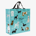 A reusable tote bag with a playful dog-themed design. The bag is a light blue color with black handles. It features a variety of dog breeds in different poses, including a bulldog, a poodle, a dachshund, and a husky. The text "People I want to meet: 1. Dogs" is printed on the bag in black.