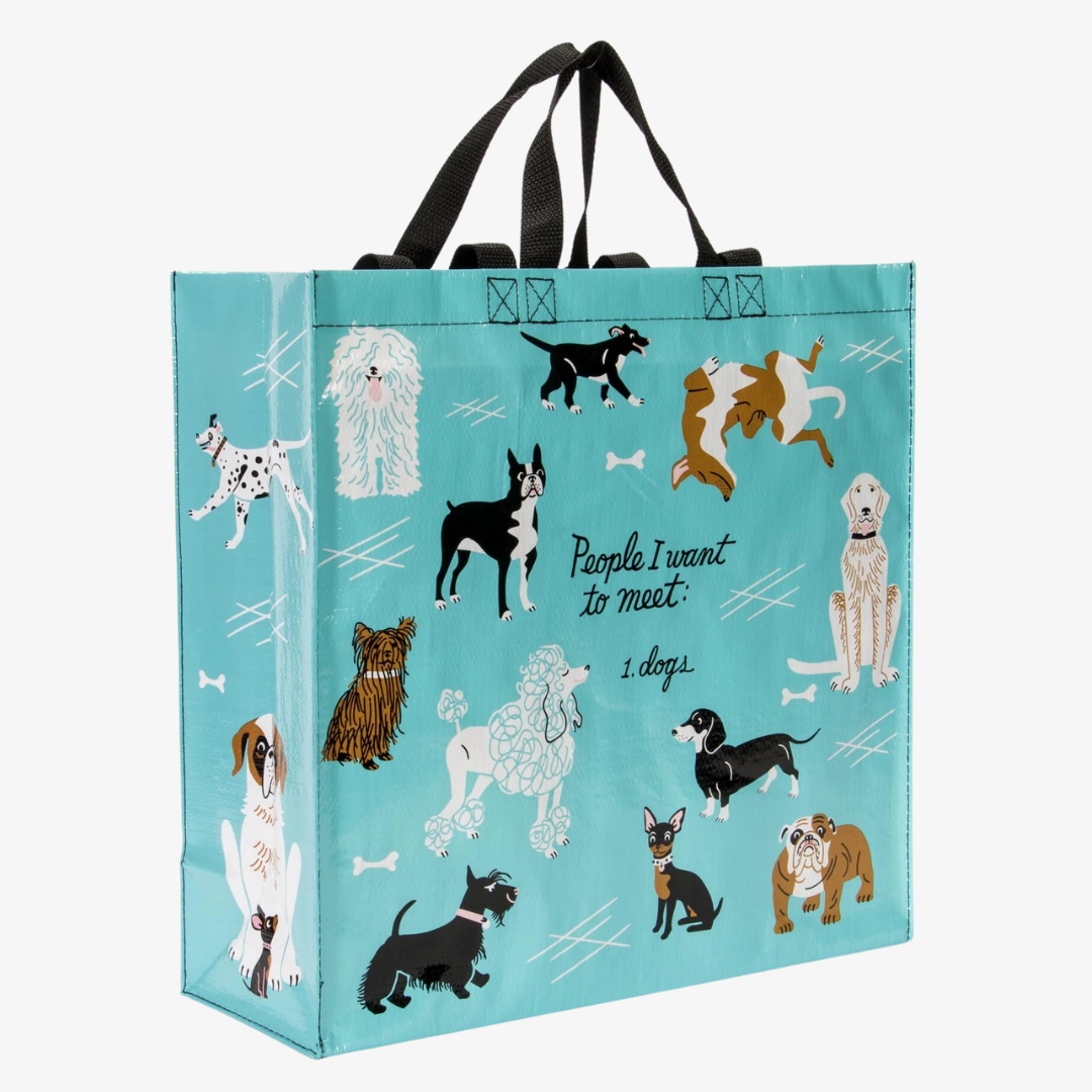 A reusable tote bag with a playful dog-themed design. The bag is a light blue color with black handles. It features a variety of dog breeds in different poses, including a bulldog, a poodle, a dachshund, and a husky. The text "People I want to meet: 1. Dogs" is printed on the bag in black.