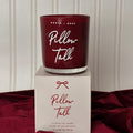 Maroon candle with 'Pillow Talk' text on top of a matching box against a neutral background