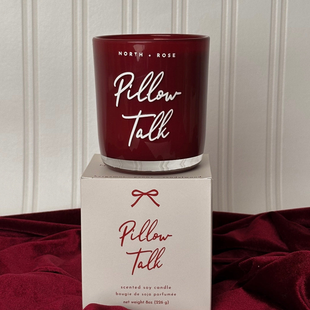 Maroon candle with 'Pillow Talk' text on top of a matching box against a neutral background
