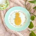 Decorative plate with a pineapple design on a textured surface with leaves.