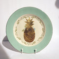 Decorative plate with a gold pineapple design on a light green rim