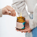 Person lighting a candle labeled 'Wilde & Wild Honey' with another person holding it.
